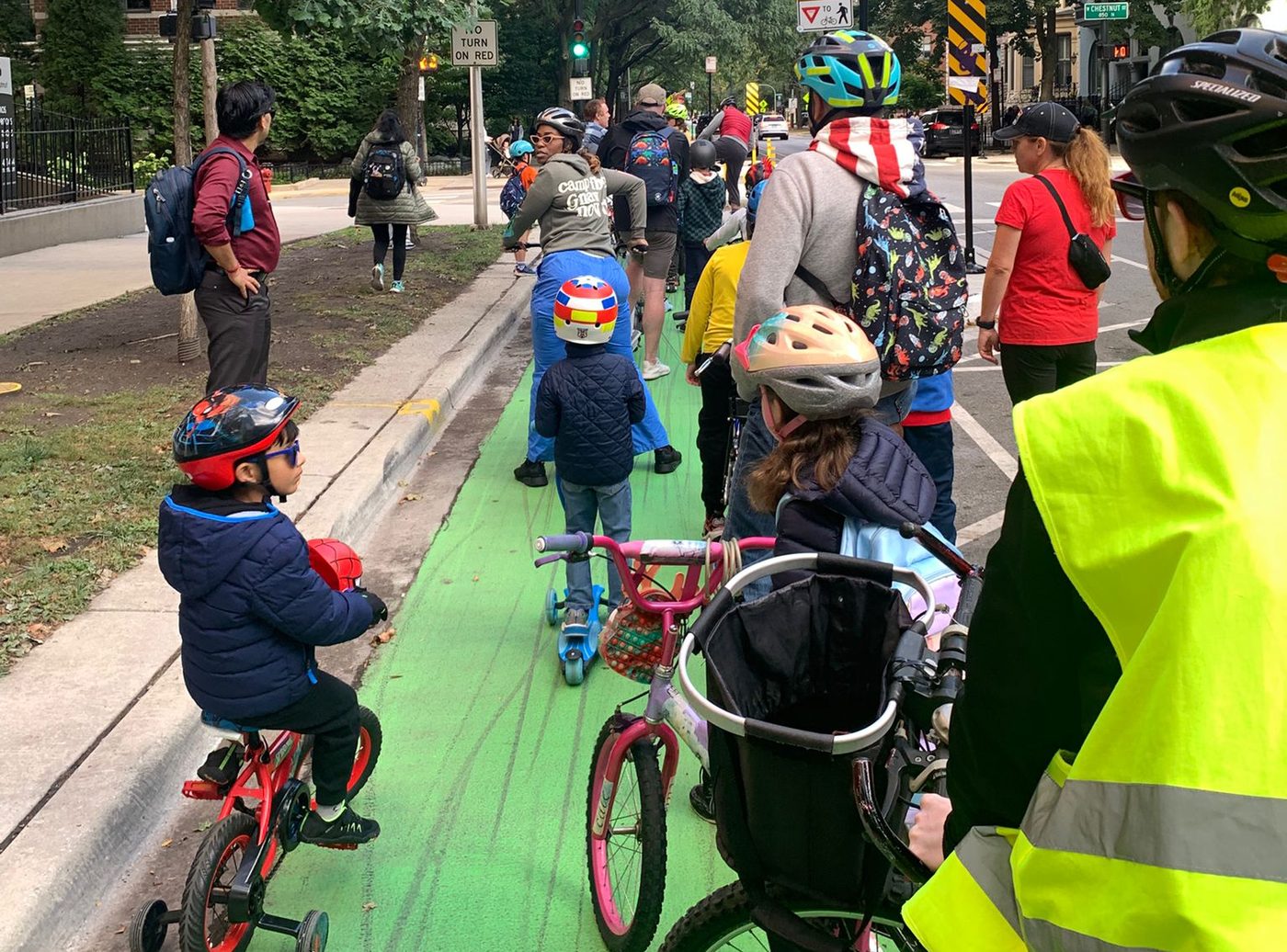 The bike bus waiting at a crossing, kids on small bikes and scooters with adults alongside