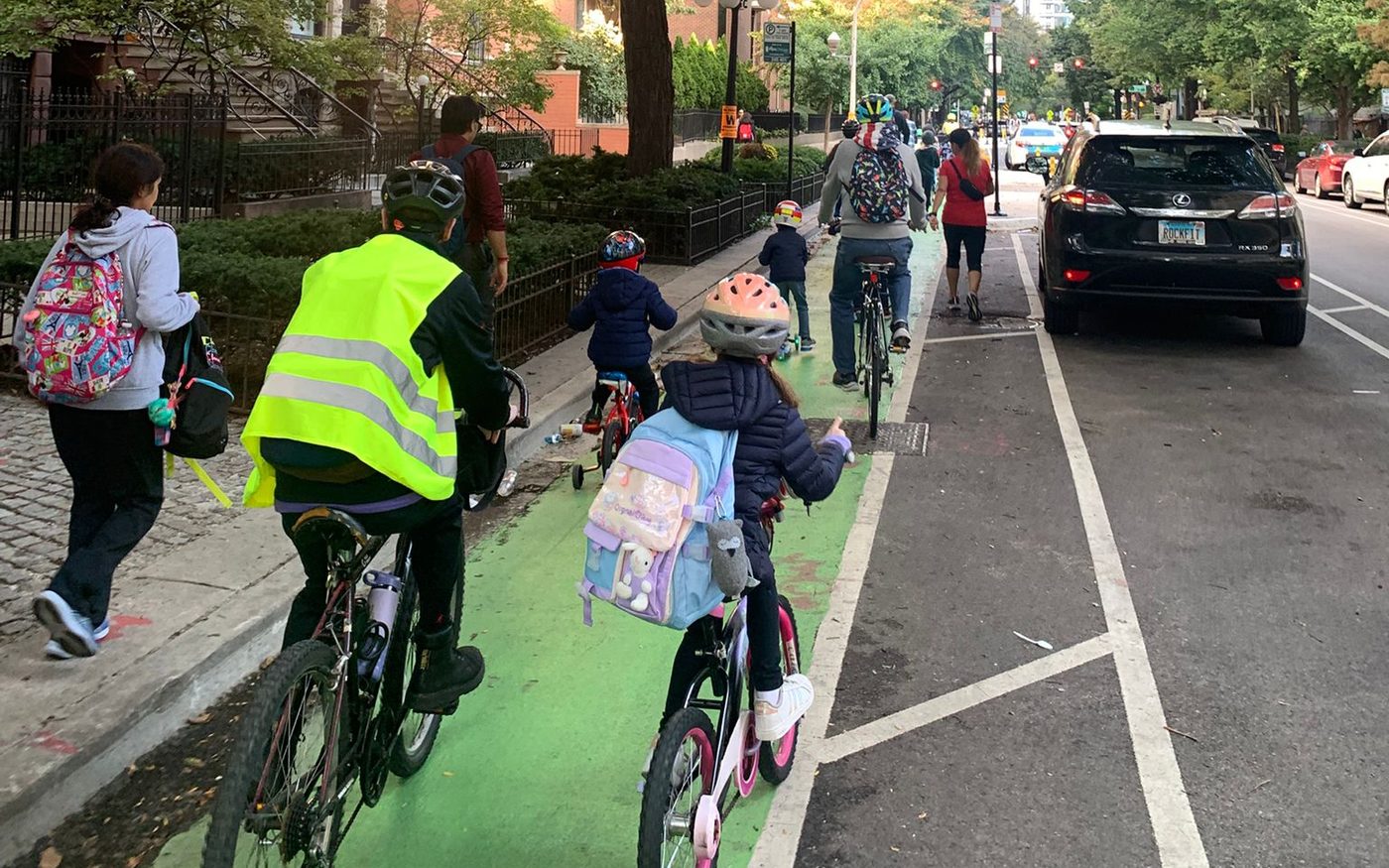 Riders in the green protected bike lane with traffic passing in the next lane